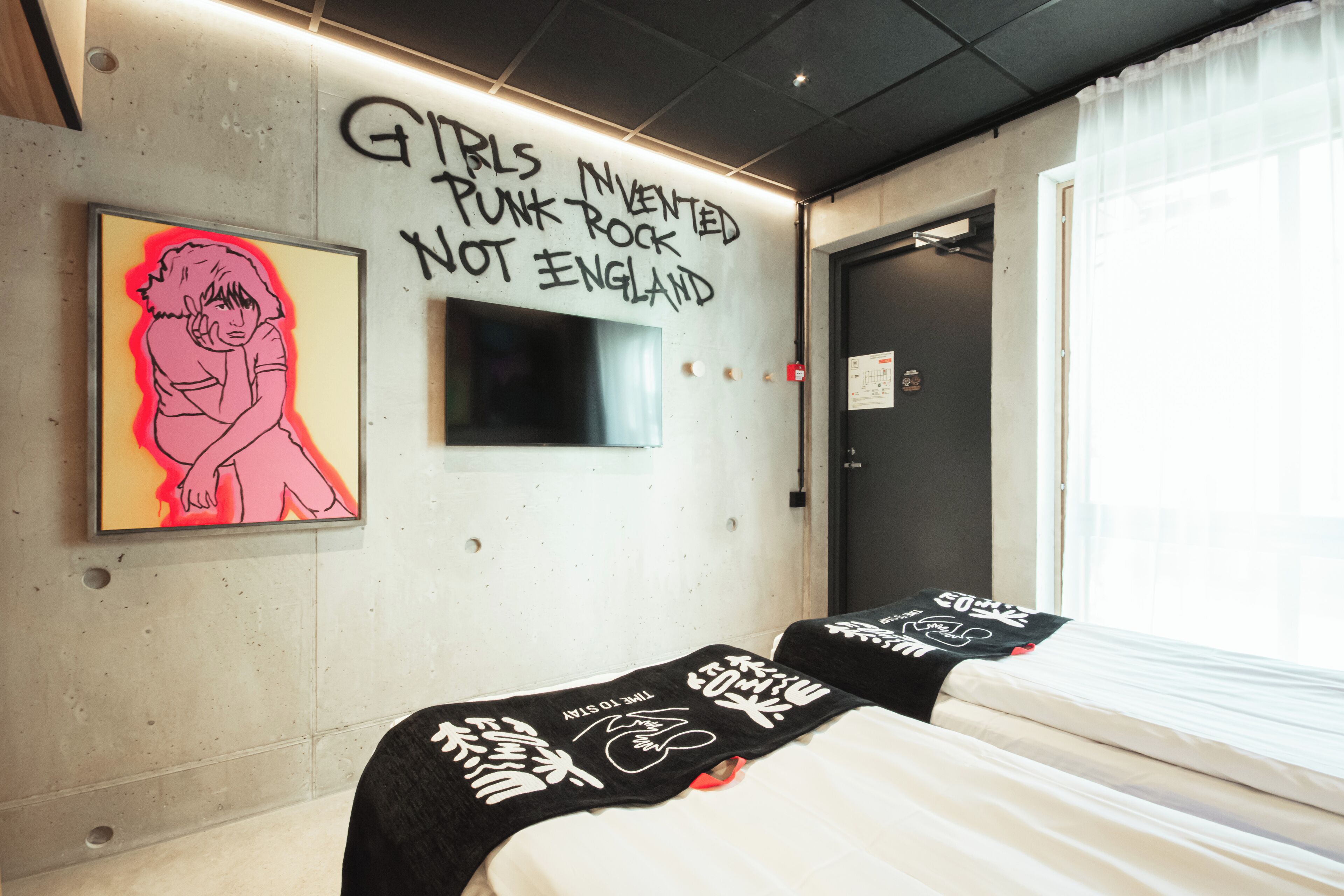 Une pièce avec un lit, un mur couvert de graffitis et une fenêtre.