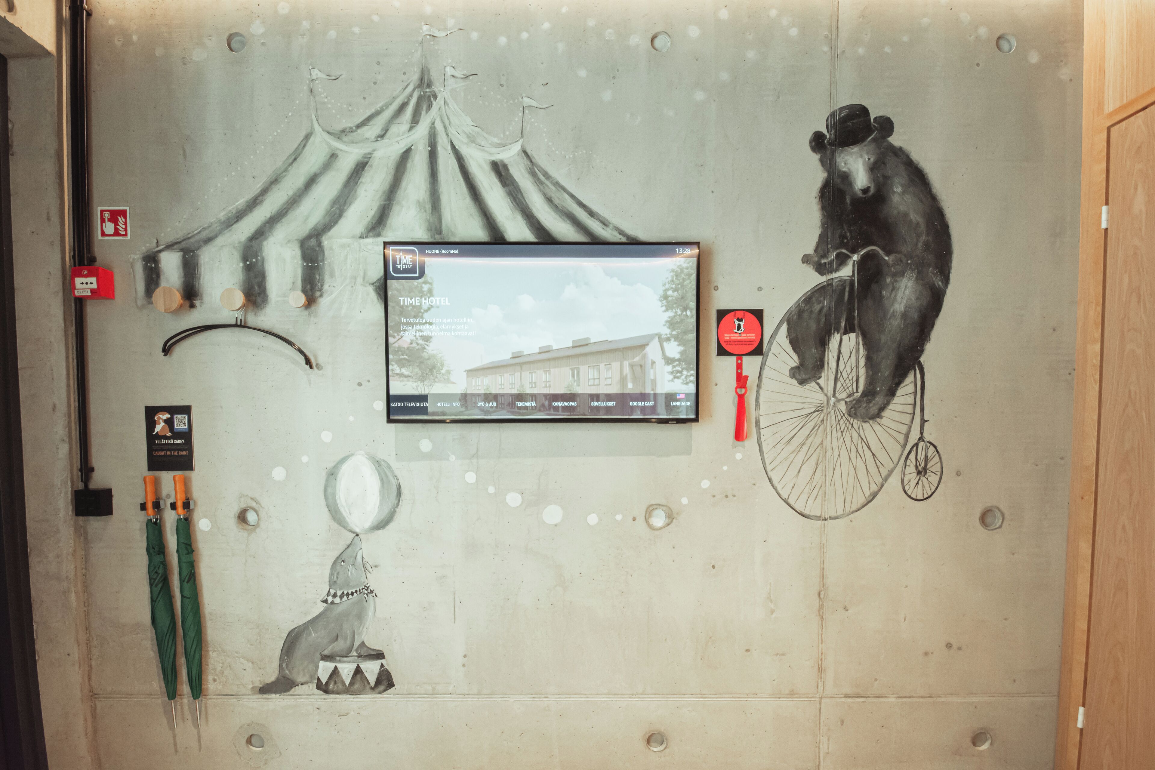 Un muro con un orso che va in bicicletta, una tenda e uno schermo televisivo che mostra un edificio.