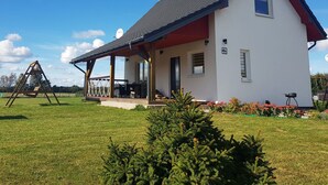 Ein weißes Haus mit rotem Dach und einer Veranda.