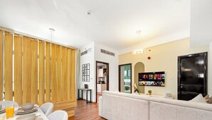 Ett modernt vardagsrum med en soffa, ett matbord med tallrikar och glas, en tv som är monterad på väggen och en avskärmande väggpanel i trä.