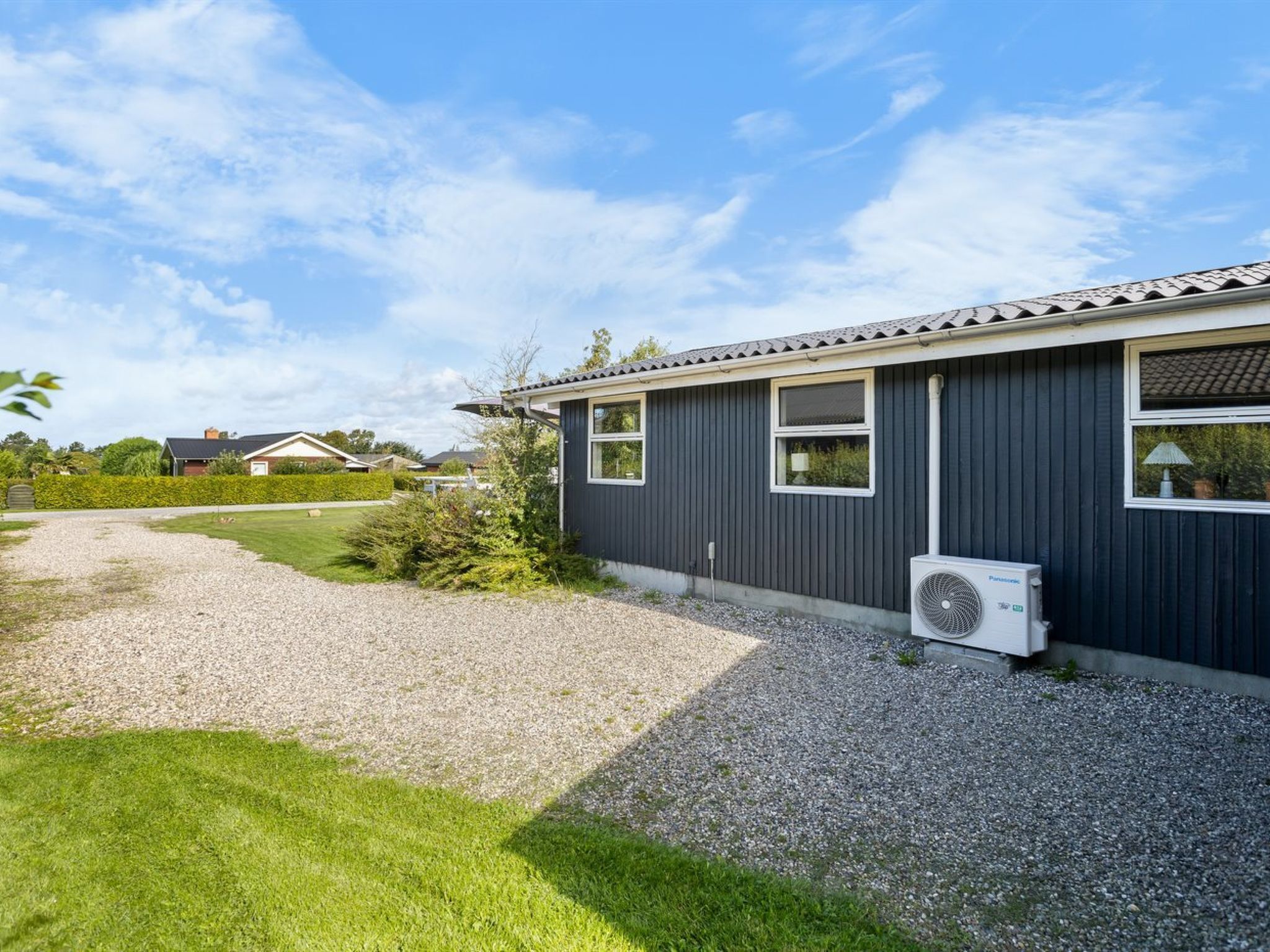 A modern house with a gravel driveway and a well-maintained lawn.