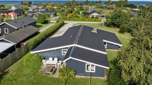 Ett bostadsområde med hus, en gräsyta och utsikt över havet.