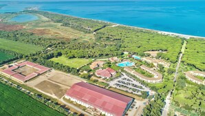 Vista aerea di un resort con diversi edifici, una piscina e un ampio prato.