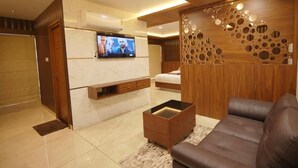 A modern living room with a flat-screen TV, a sofa, a coffee table, and a decorative wall panel. - Mountain View Tourist Home (Thamarassery)