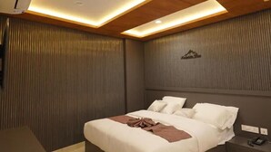 A modern bedroom with a bed, bedside tables, and a wall-mounted air conditioning unit. - Mountain View Tourist Home (Thamarassery)