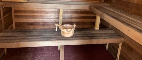 A sauna with wooden benches and a wooden bucket.