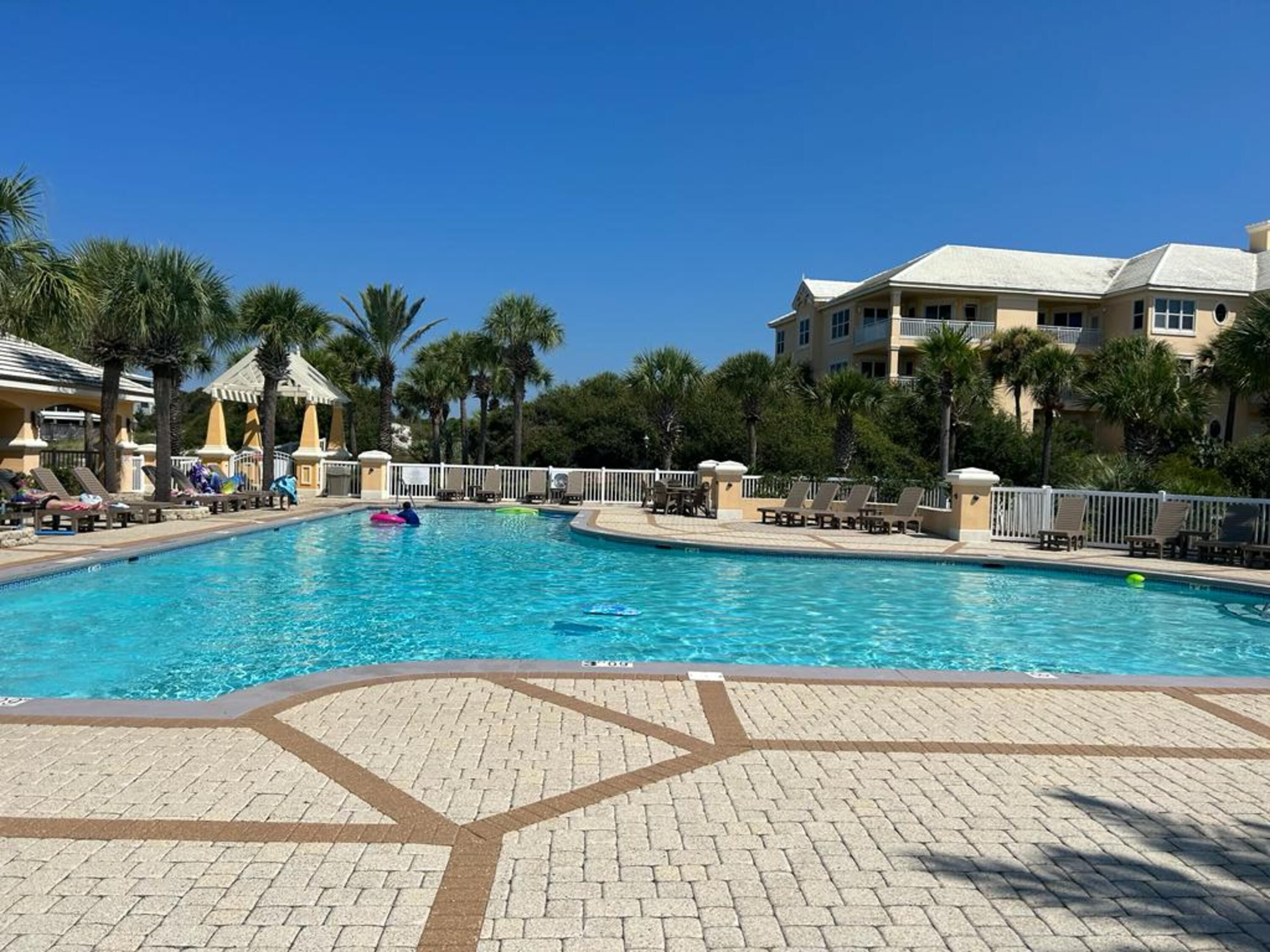 A swimming pool with lounge chairs and palm trees.