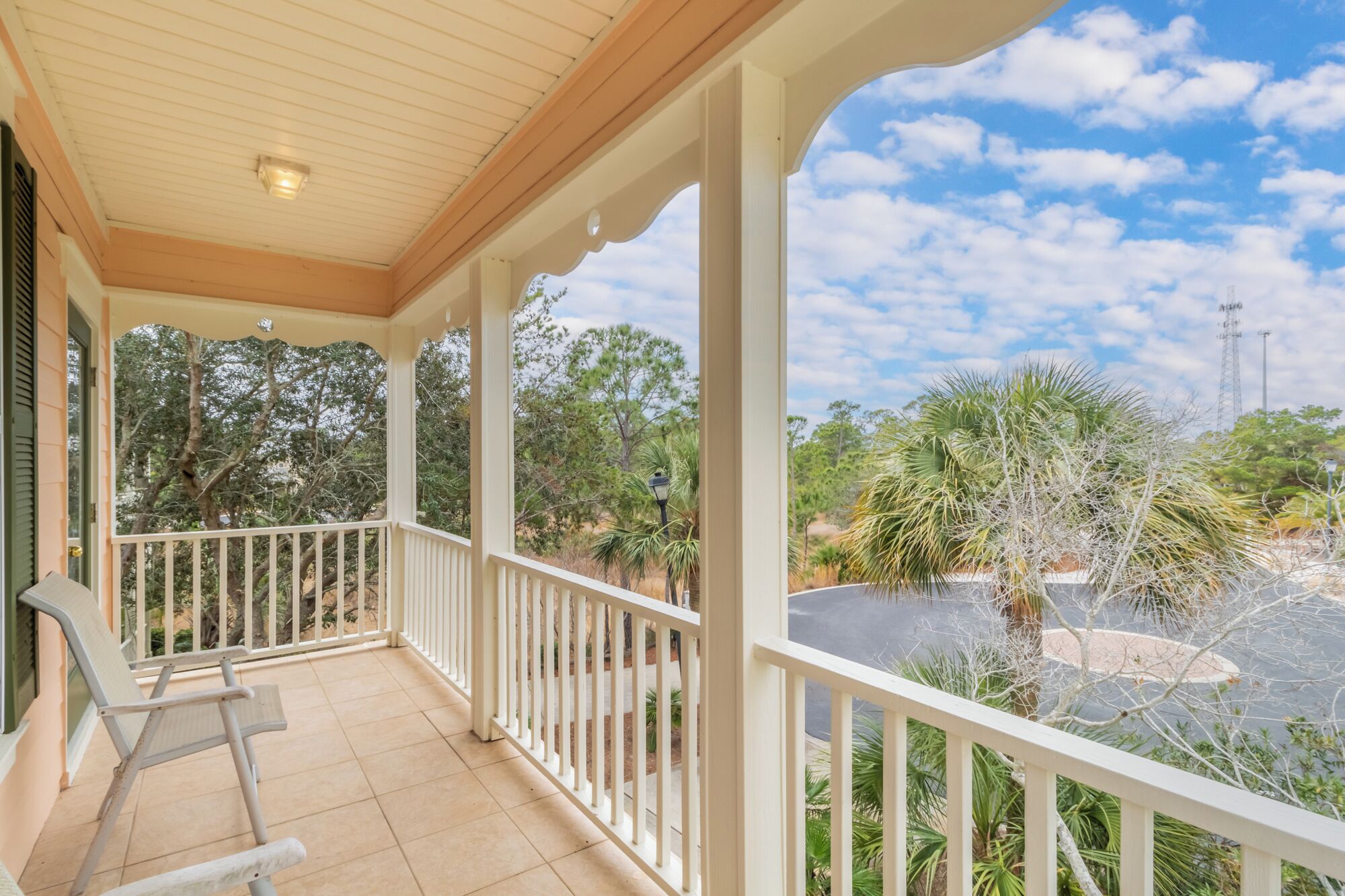 A covered porch with a view of a parking area and surrounding trees.