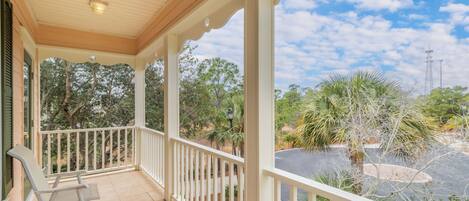 A covered porch with a view of a parking area and surrounding trees.