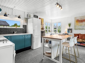 Une cuisine moderne avec des meubles de couleur turquoise, un réfrigérateur blanc et une table à manger en bois.