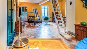 A spacious living area with a staircase, a sofa, a coffee table, and a green chair. - Cosy apartment for 4 people with WIFI, pool, TV, patio and pets allowed (Dolcedo)