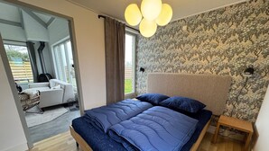 A bedroom with a bed, a headboard, a nightstand, and a wall with a tree pattern.