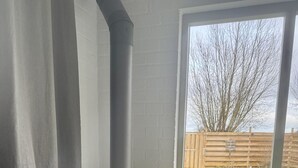 A room with a large window, a fireplace, and a dog.