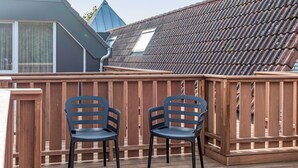 Eine Holzterrasse mit zwei schwarzen Stühlen und einem Holzzaun.