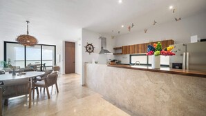 Une cuisine moderne dotée d’un plan de travail en marbre, de meubles en bois et d’un vase décoratif rempli de fleurs colorées.