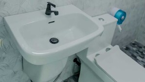 A bathroom with a white sink, a mirror, and a toilet. - Rungmod 99 Villa (Khanom)