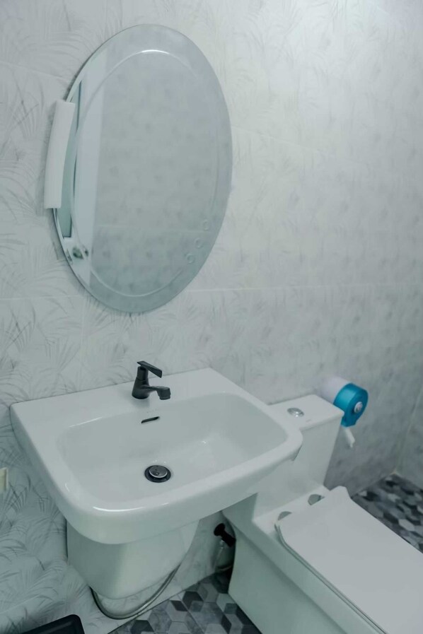 A bathroom with a white sink, a mirror, and a toilet.