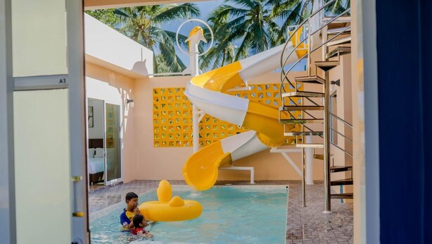 A pool area with a water slide and a child playing in the water. - Rungmod 99 Villa (Khanom)