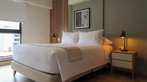 Un dormitorio moderno con una cama grande, una mesita de noche con lámpara y un cuadro en la pared.