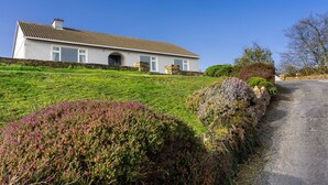 Een huis met twee verdiepingen, een stenen fundering en een dak van dakpannen, met een verharde oprit.