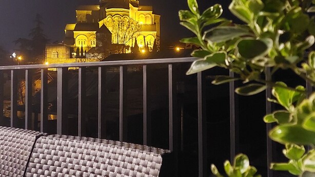 A building with a golden dome and multiple illuminated structures at night. - Falcon Boutique Hotel (Tbilisi)
