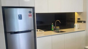 Et moderne køkken med hvide skabe, et rustfrit stål køleskab, en vask og en kaffemaskine.