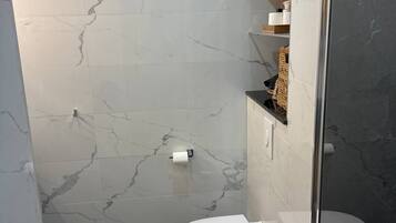 Une salle de bain moderne avec des toilettes, un espace douche et des carreaux de marbre.