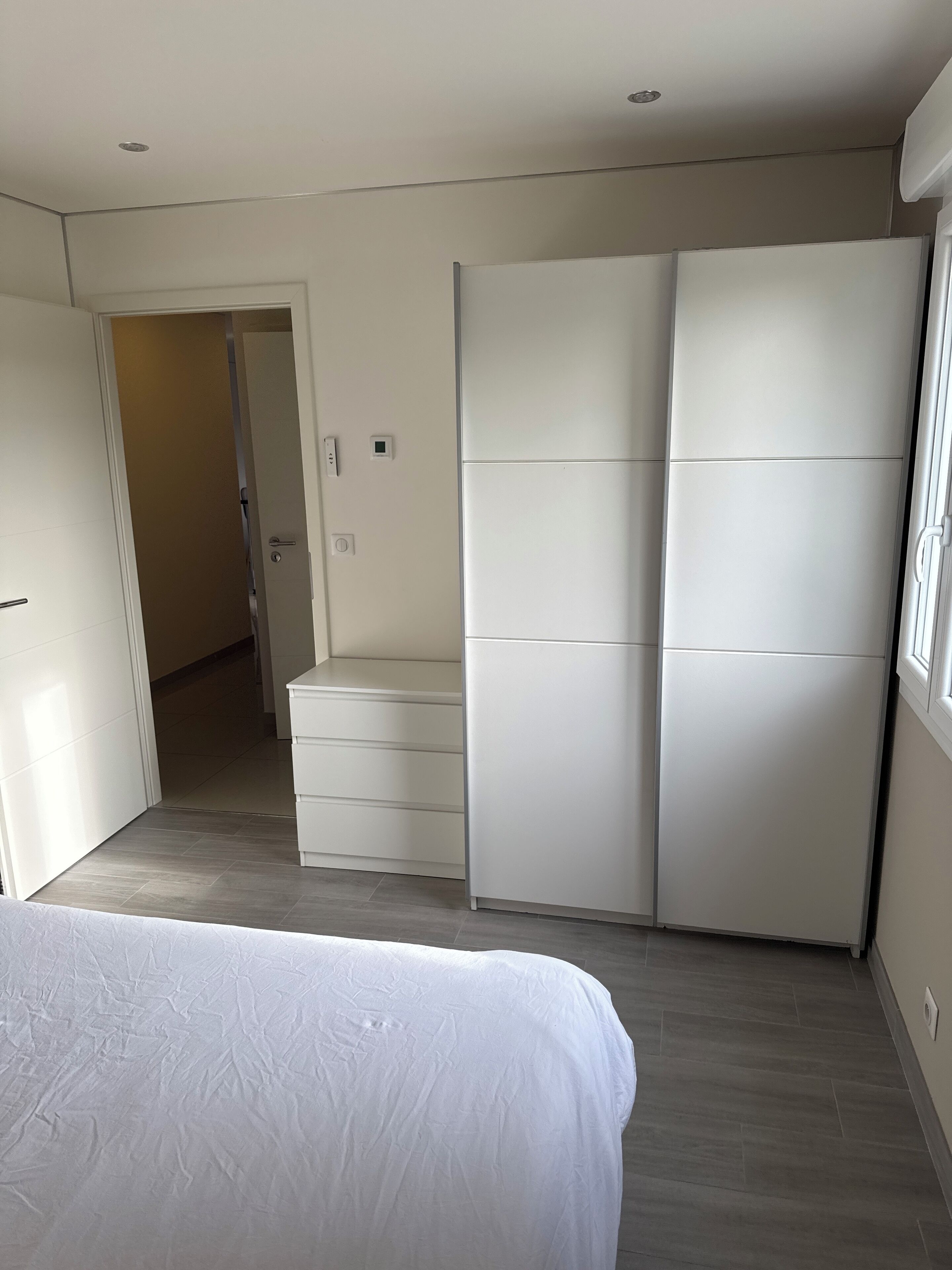 Une chambre à coucher comprenant un lit, une armoire et une porte donnant sur une autre pièce.