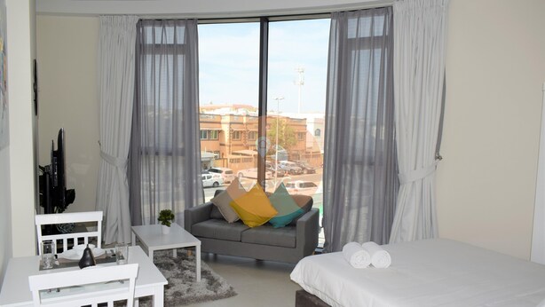 Ett hotellrum med en säng, en soffa, ett litet bord och en tv.