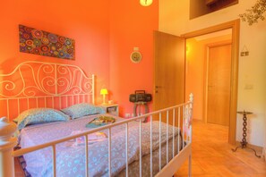 A bedroom with a bed, a bedside table with a lamp, a radio, and a wall clock. - Positano Villa with View - Large Garden and Private Pool - 3 bedrooms 2 bathrooms (Lazio)