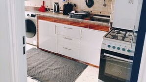 A compact kitchen with white cabinets, a gas stove, a washing machine, and a tiled backsplash. - Beautiful home ground in Tangier Beau Site Parking  (Tanger)