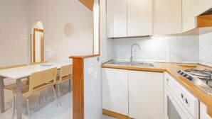 Een keuken met witte kasten, een houten aanrecht, een spoelbak en een fornuis.