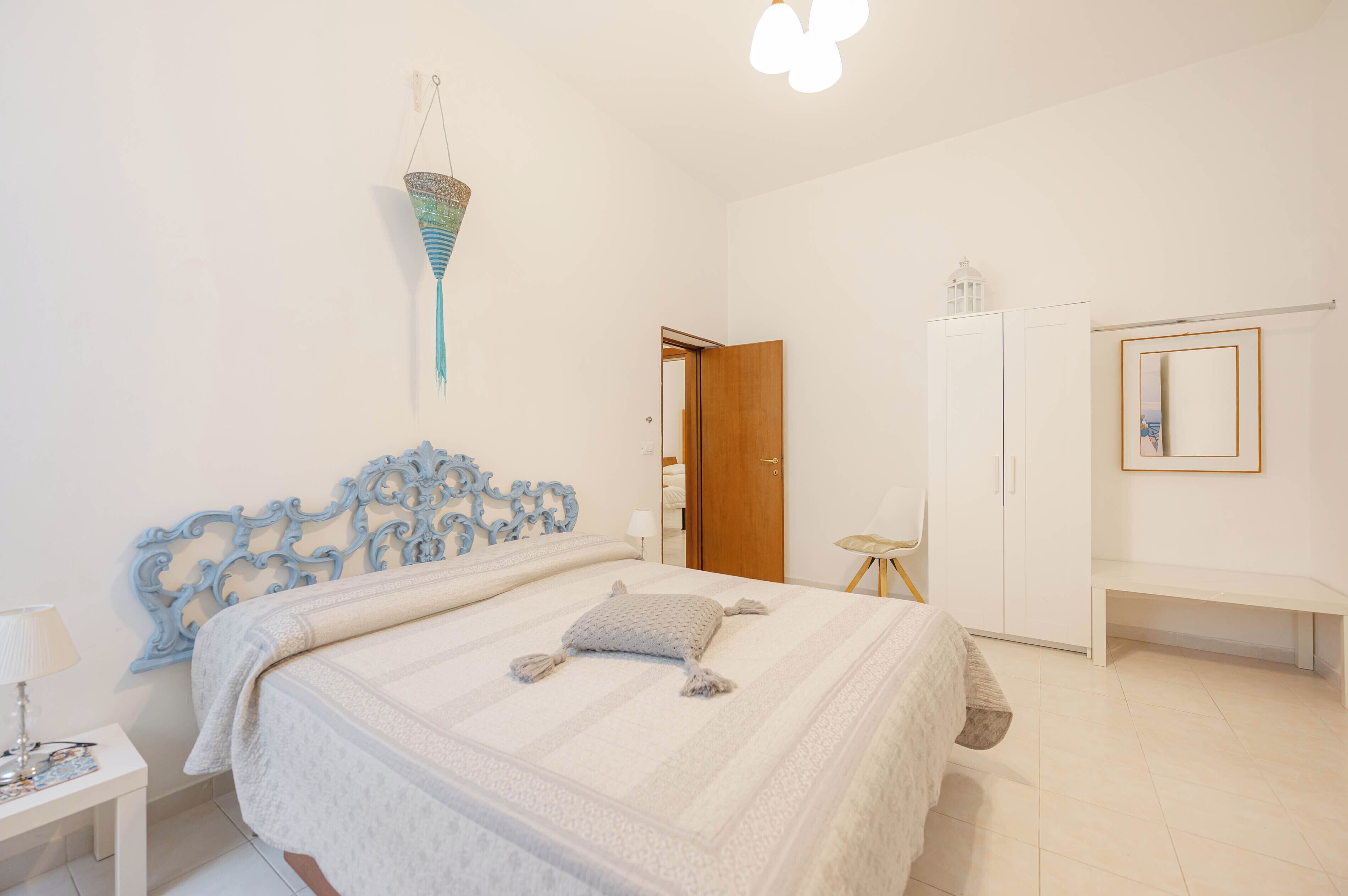 Un dormitorio con cama, mesita de noche, armario y espejo.