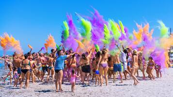 A beach scene with people enjoying a colorful powder event.