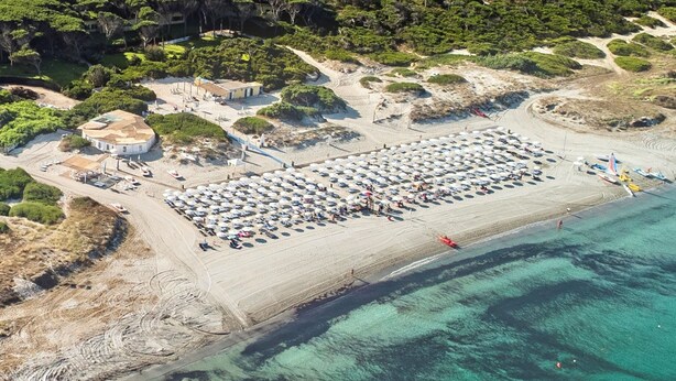 Oversigtsbillede af en strand med et stort parkeringsområde, en mindre bygning og en båd på vandet.
