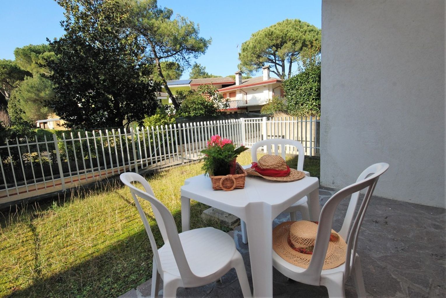 A patio with a white table and chairs, a basket, and a hat.