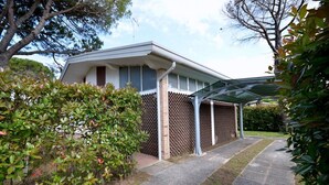 A modern house with a covered porch, a brick wall with a diamond pattern, and a paved driveway.