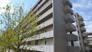 A multi-story parking garage with a modern design, featuring a series of balconies and a pedestrian bridge.