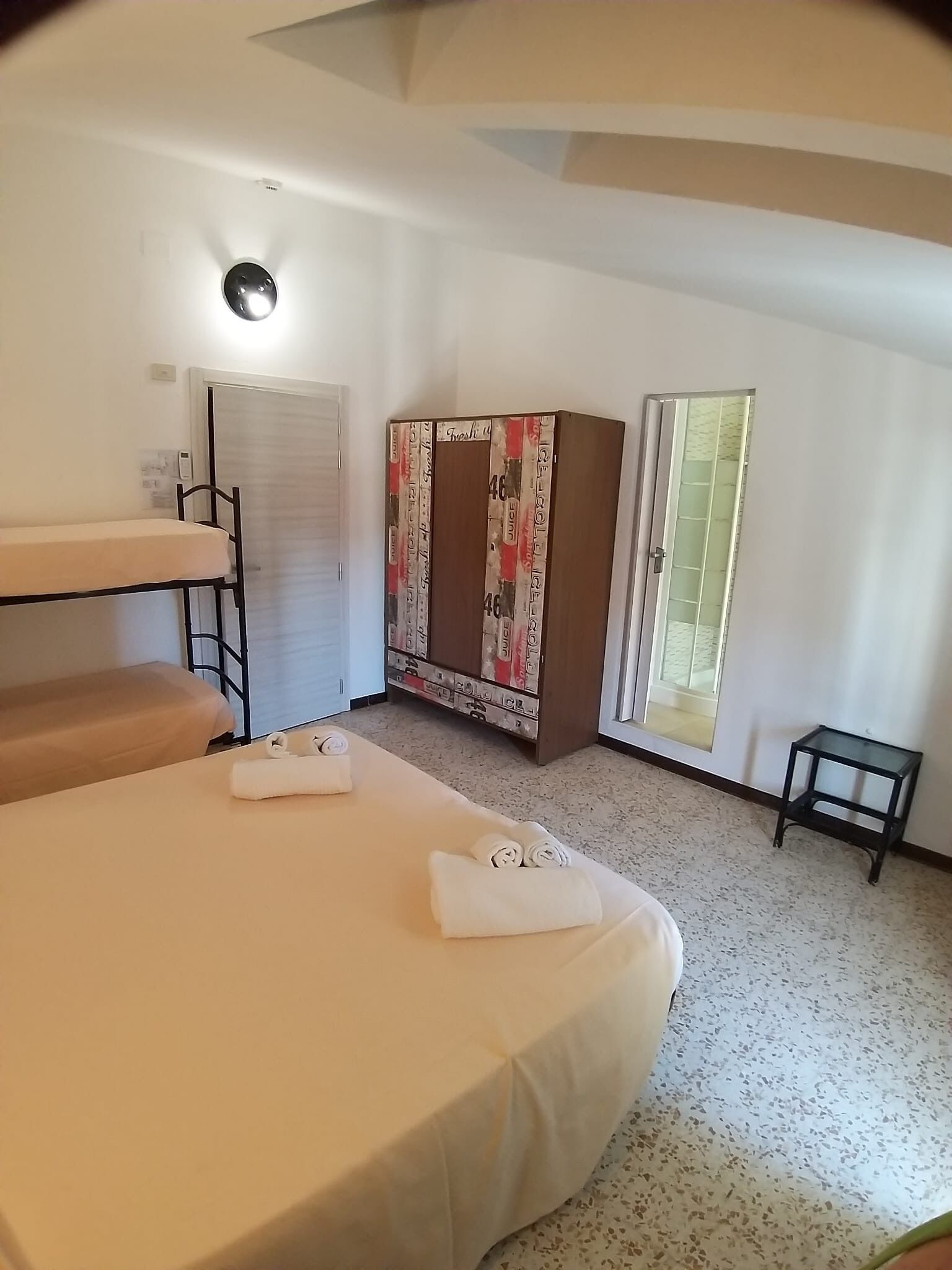 A room with bunk beds, a wardrobe, a small table, and a window.