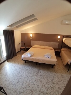 Una habitación de hotel con una cama, una silla, un escritorio y un ventanal con cortinas.
