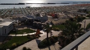 A coastal hotel with multiple umbrella-covered seating areas, a pool, and a view of the sea. - Hotel Ideal  (Rimini)