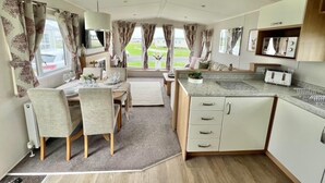 A compact kitchen with a dining area, a small island, and a view of the outdoors. - 3bed-8berth- Hot Tub-mablethorpe-pet Friendly-wifi (Mablethorpe)