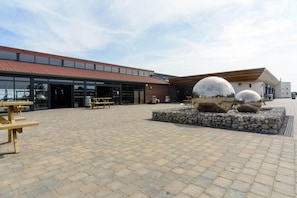 A building with a red-tiled roof and a paved courtyard with stone benches and spherical sculptures. - 3bed-8berth- Hot Tub-mablethorpe-pet Friendly-wifi (Mablethorpe)
