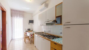 Cucina con mobili bianchi, piano cottura a gas, lavello e microonde.