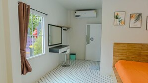 Ein kleiner, sauberer Raum mit einem Bett, einem Spiegel, einem Waschbecken und einer Tür.