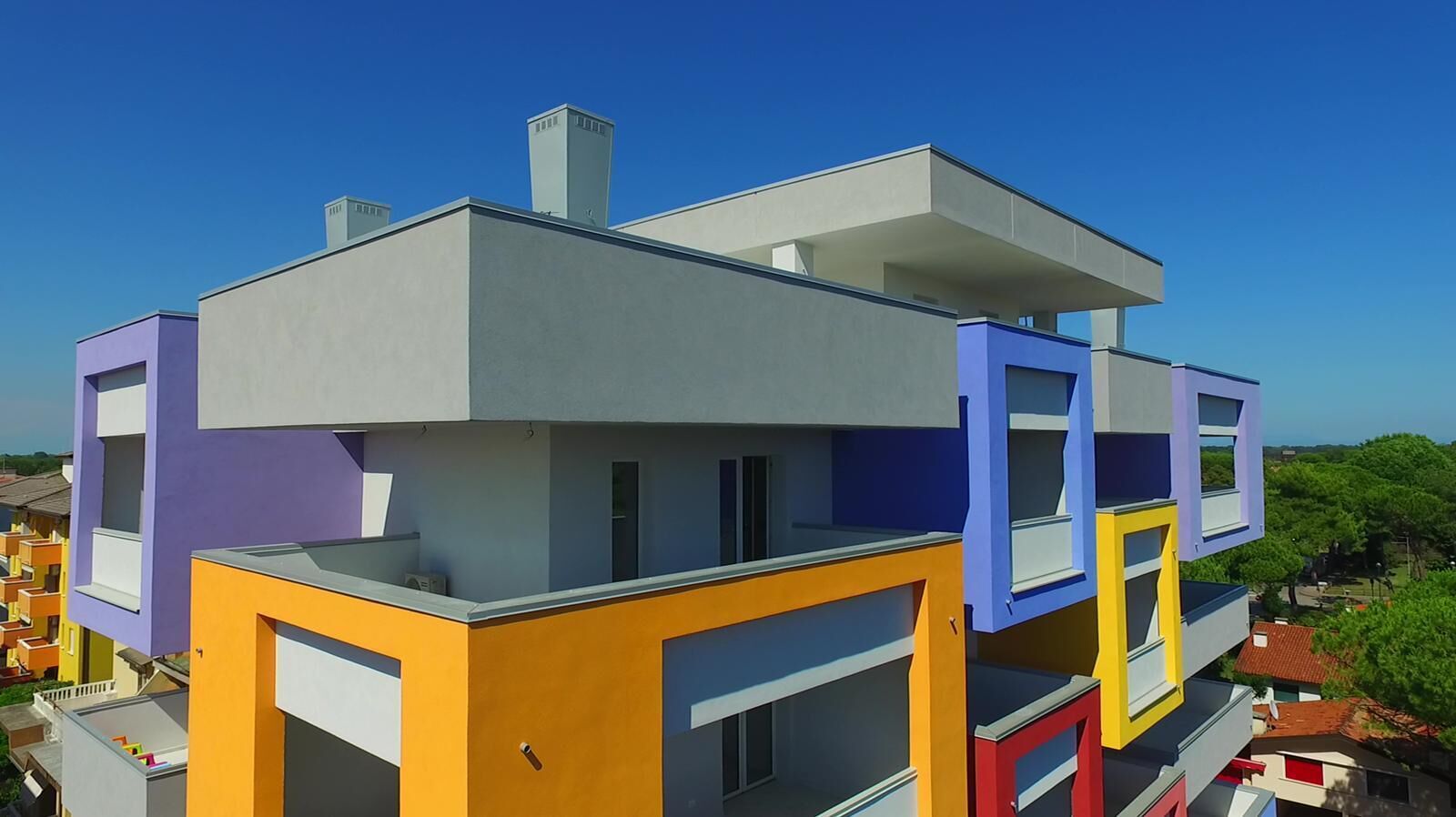 A multi-story building with a flat roof, a chimney, and balconies.
