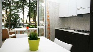 Une cuisine moderne avec des meubles blancs, une cuisinière à gaz et un coin repas comprenant une table et des chaises blanches.