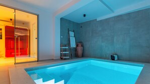 A modern indoor swimming pool with clear blue water, a glass door entrance, and a concrete wall. - Beachfront Villa, Indoor Heated pool with Stunning view (Vinišce)