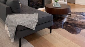 Una sala de estar moderna con chimenea, un sofá modular, una mesa de centro redonda y un gran elemento decorativo en la pared.