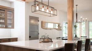 Una cocina moderna con una isla grande, armarios de madera e iluminación colgante.